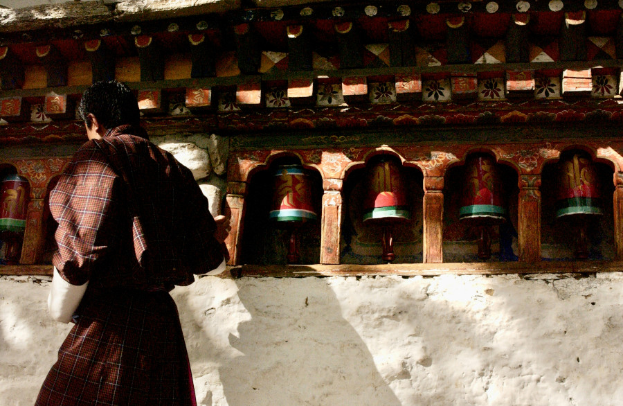 Post prayer wheels and bhutanese monk